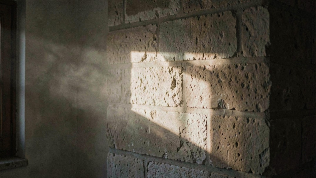Un faisceau de projection frappe un mur clair dans une pièce sombre, tâche lumineuse rectangulaire sur la pierre